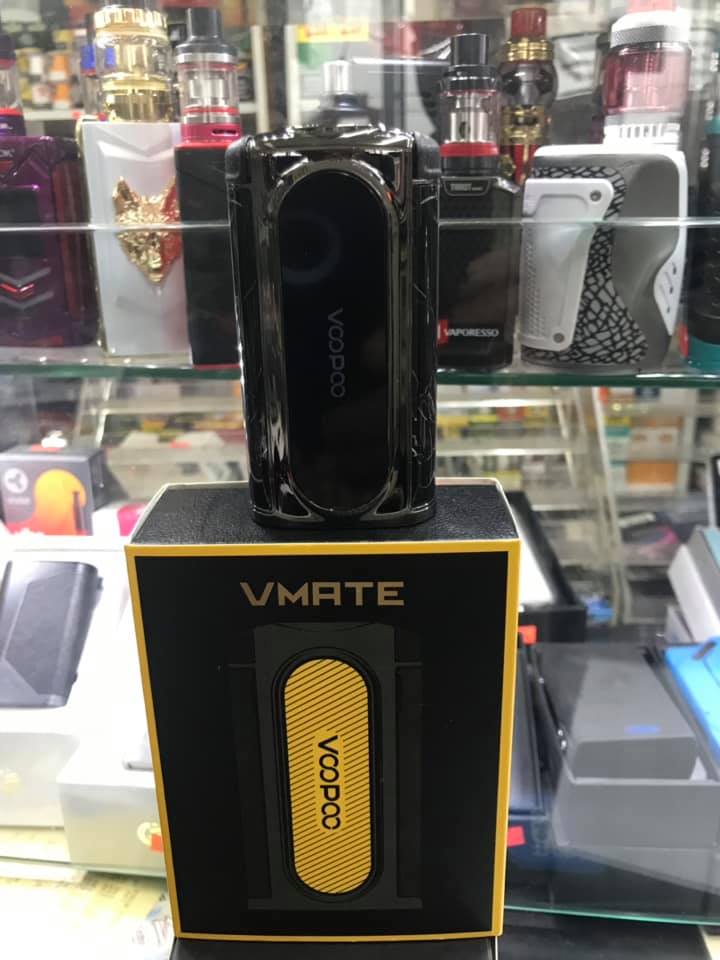 Black Voopoo Vmate vape mod on box. Display case with other vape devices visible behind.